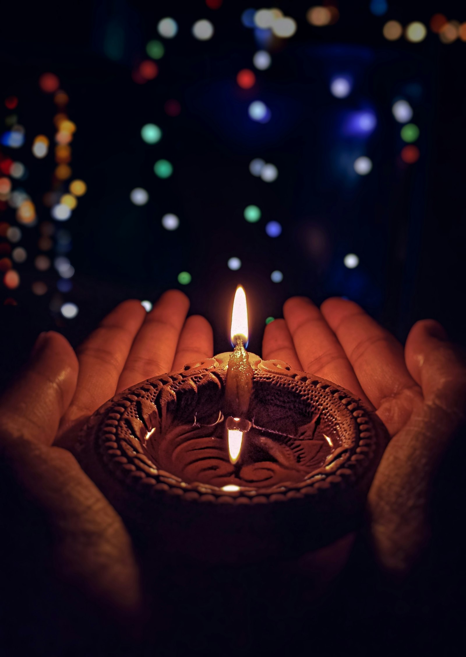 Hands holding a lit diya during Diwali