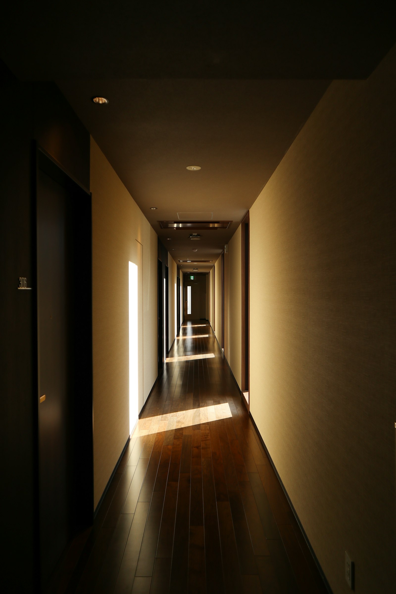 Warmly lit hotel corridor with a row of identical room doors